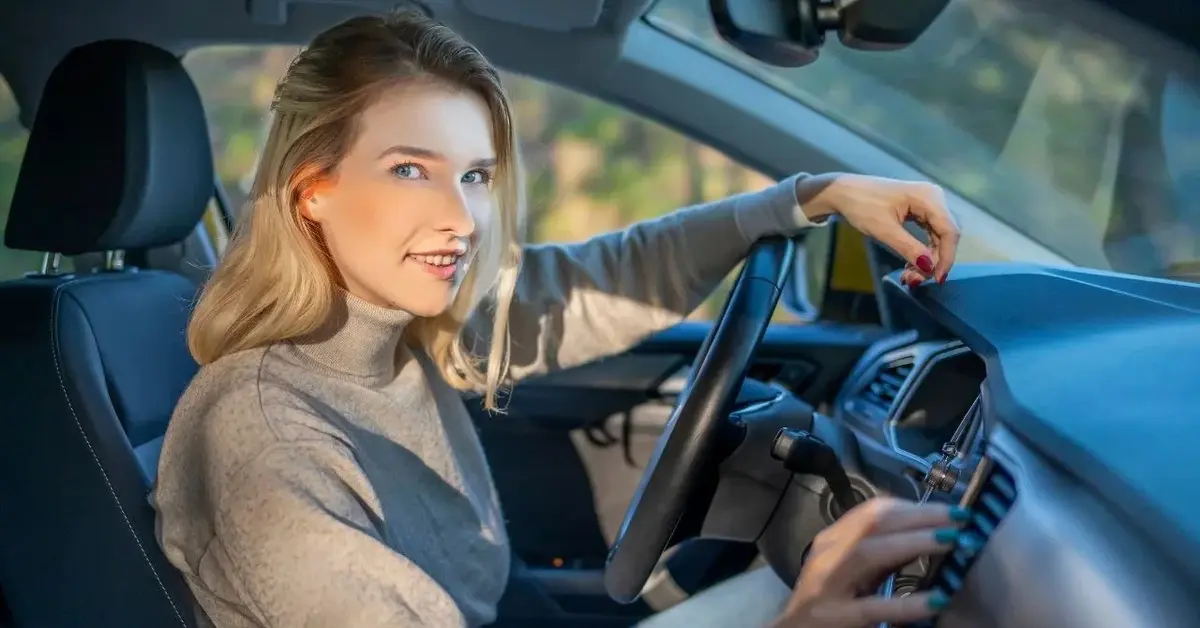 Kobieta za kierownicą samochodu dotyka deski rozdzielczej