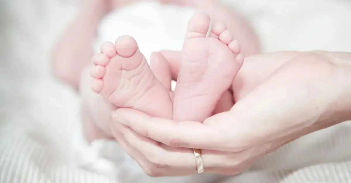 Stópki niemowlaka trzymane w dłoniach rodzica
