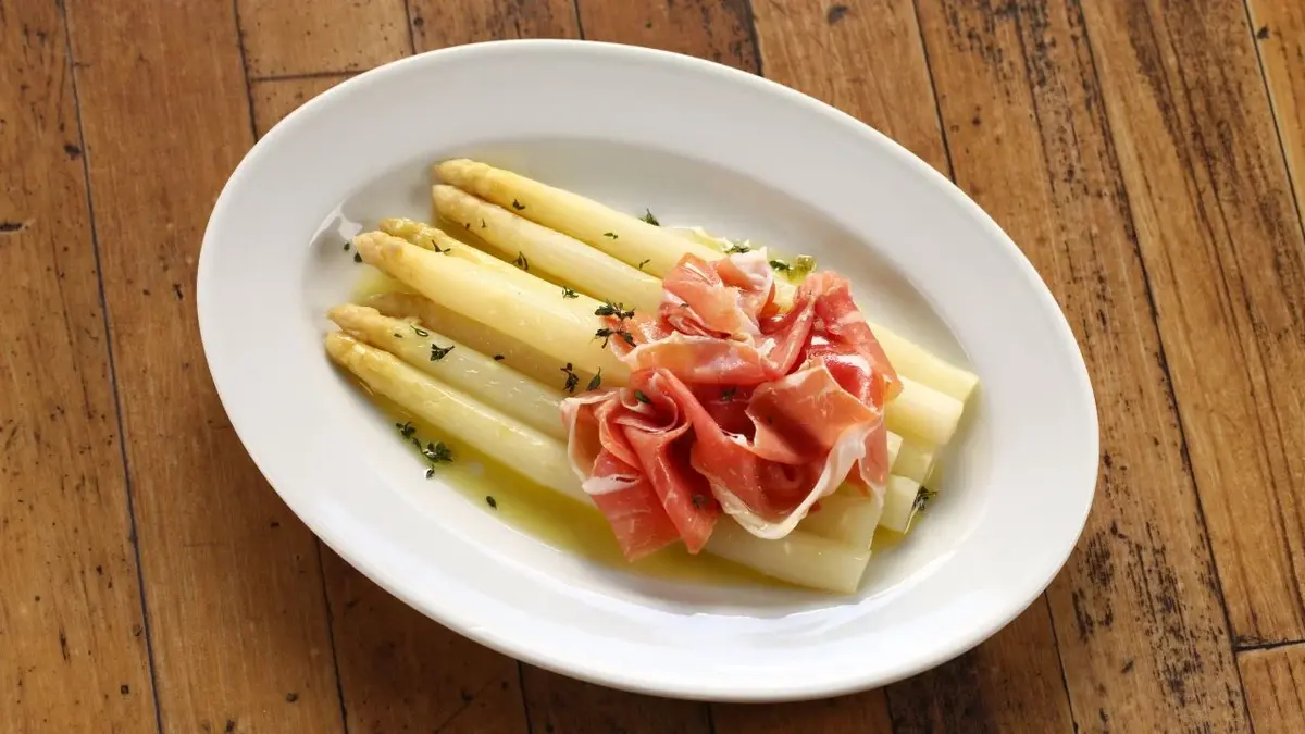 Szparagi podane z szynką włoską na białym talerzyku