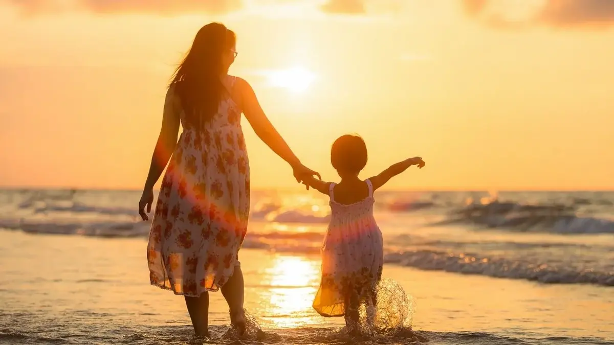 mama i córka spacerują plażą przy zachodzie słońca