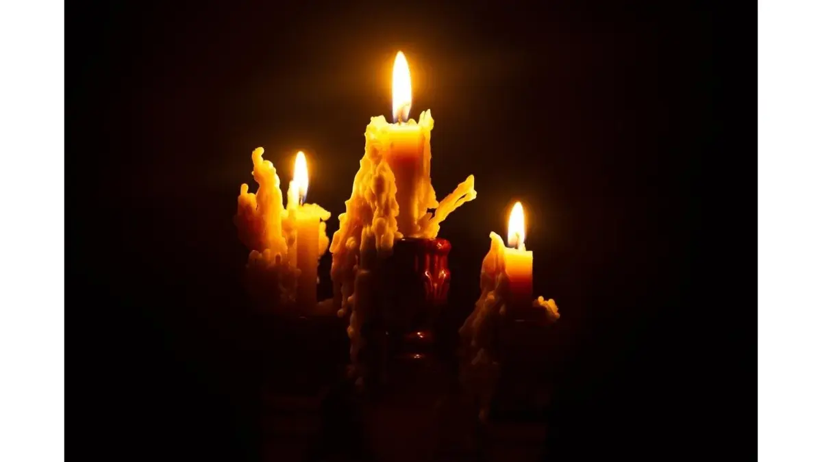 Płonące w ciemności świeczki pokryte stopionym woskiem.