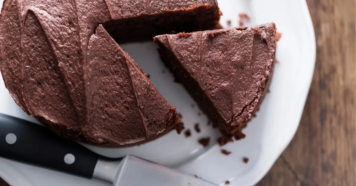 ciasto czekoladowe z fasoli okrągłe z odkrojonym trójkątem i nożem obok