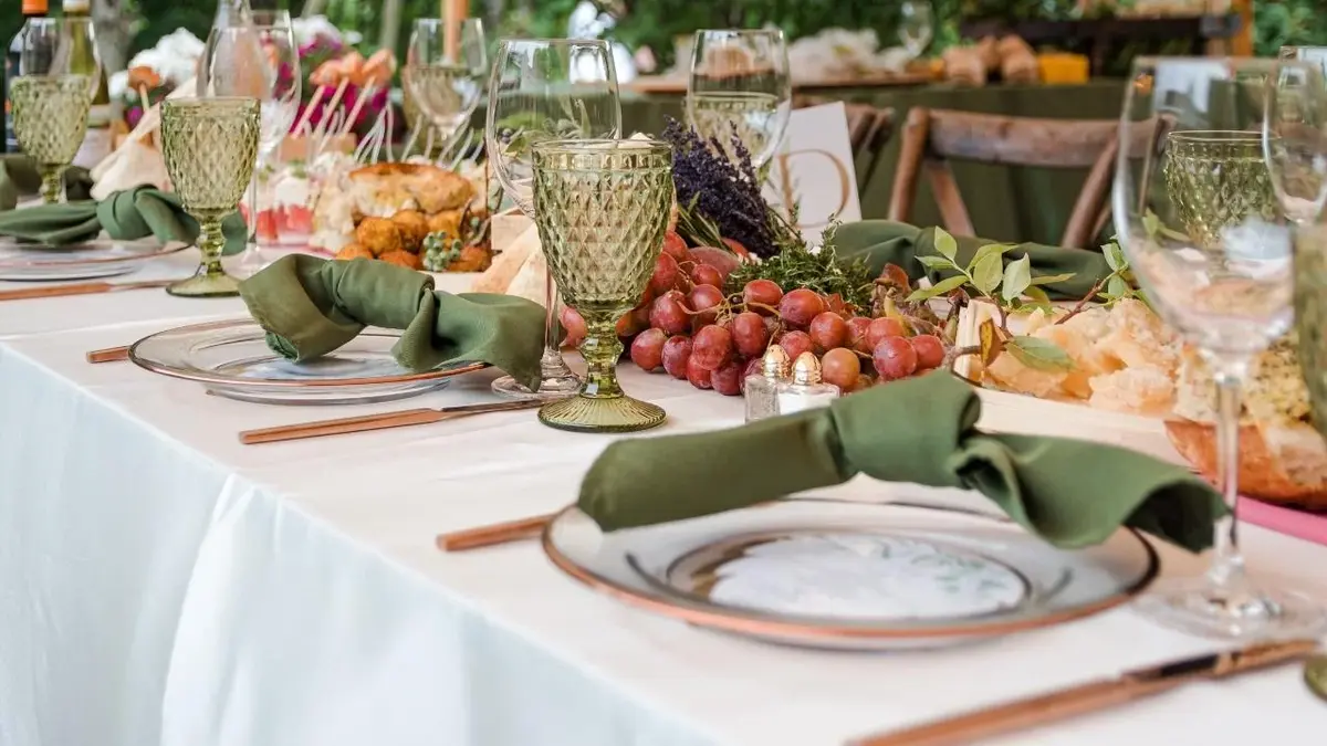 Stół weselny z talerzami, sztućcami, owocami i kieliszkami.