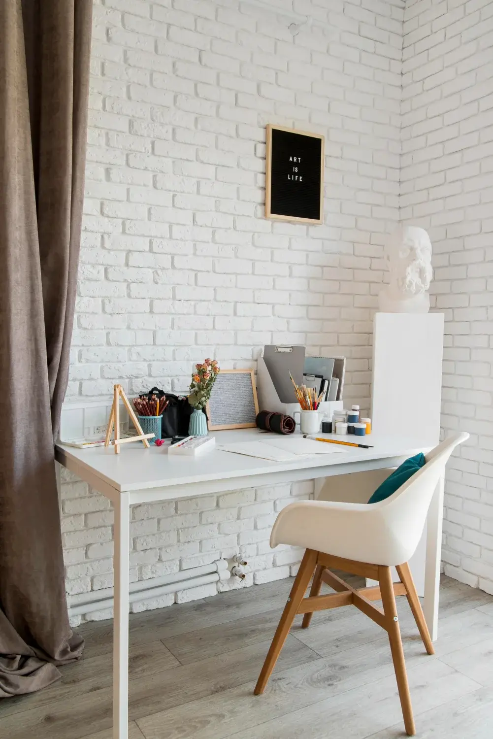 Białe biurko z drewnianym krzesłem przy białej ceglanej ścianie w nowoczesnym stylu