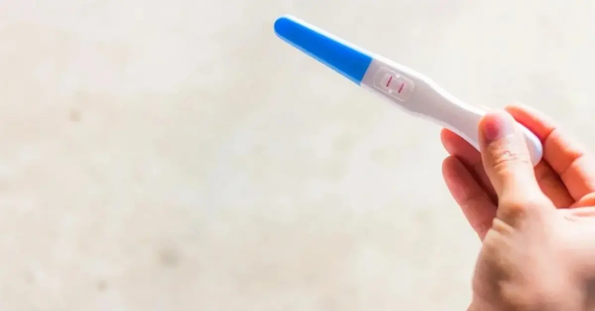 Na zdjęciu jest ręka z pozytywnym testem ciążowym.