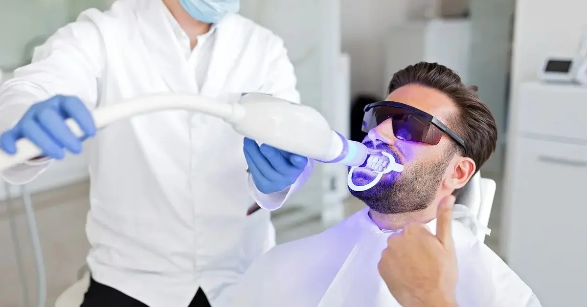 mężczyzna u stomatologa wybiela zęby 