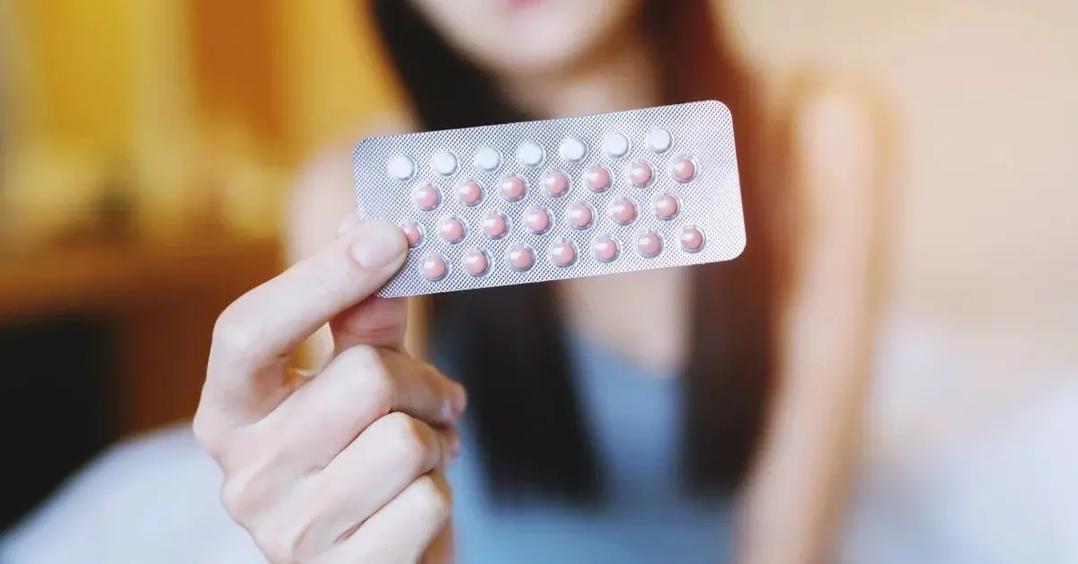 Listek tabletek antykoncepcyjnych trzymanych przez kobietę