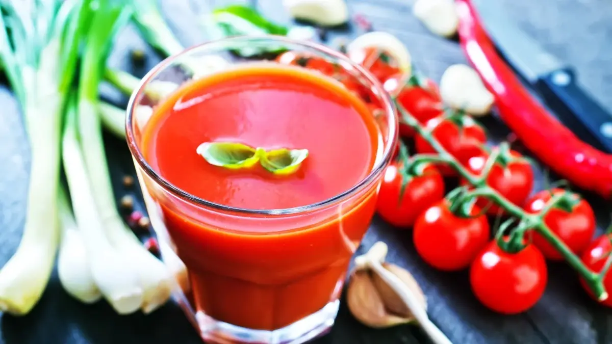 Sok pomidorowy  w szklance, obok pomidorki i warzywa