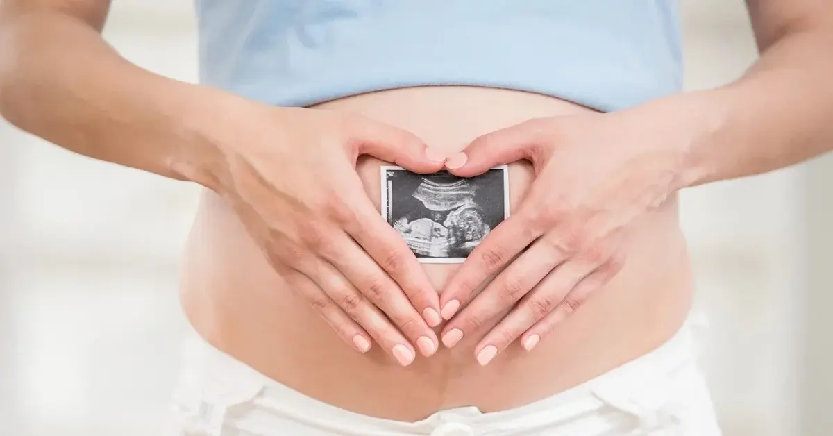 Kobieta w ciąży trzymająca przed brzuchem zdjęcie usg