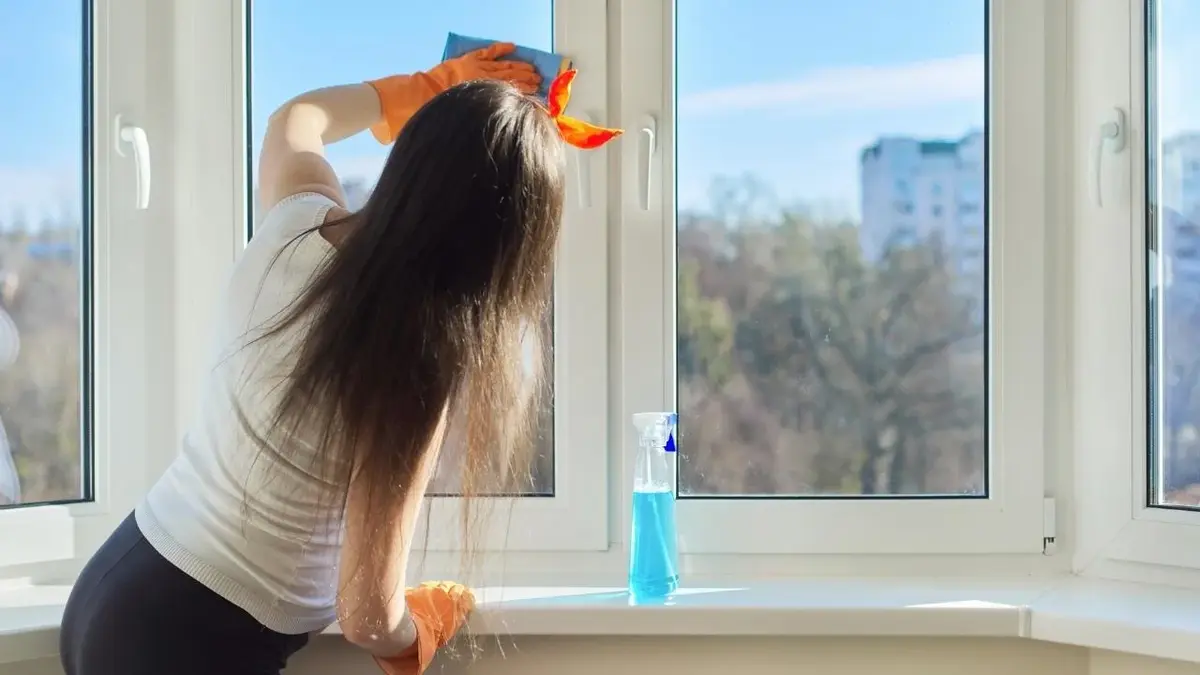 Kobieta w ciąży myjąca okno 