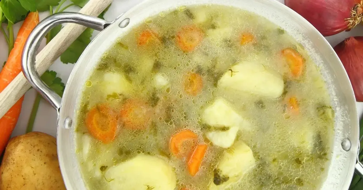 zupa z ziemniakami marchewką w garnku na tle warzyw