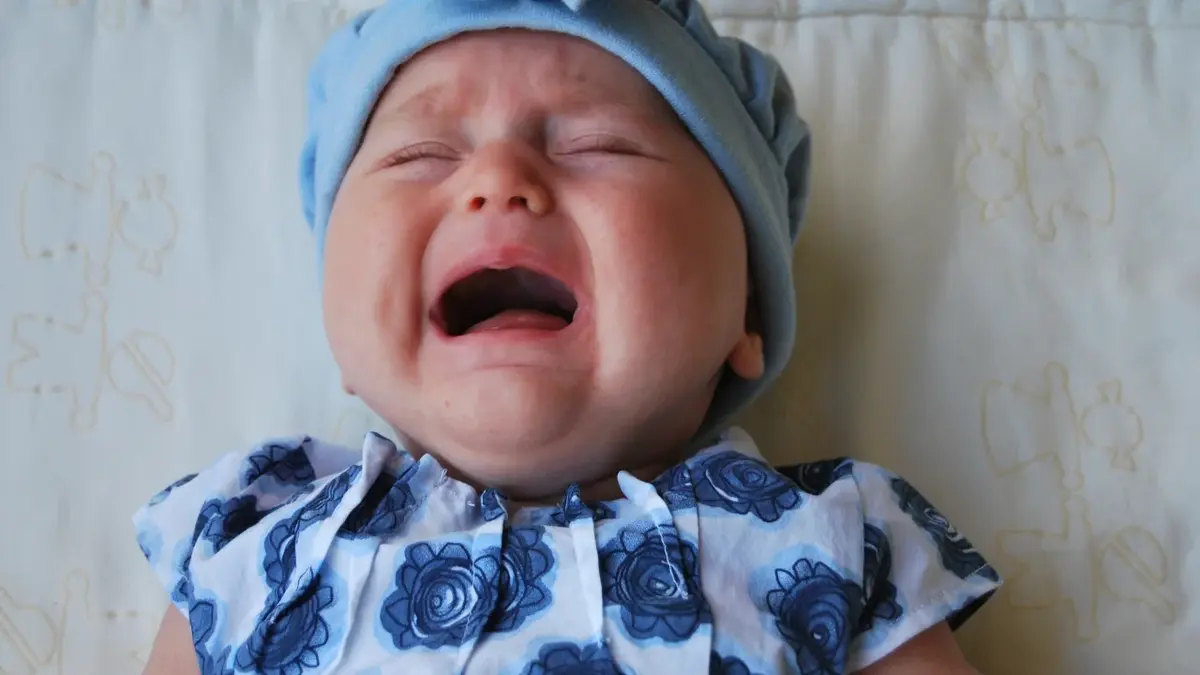płaczące dziecko w niebieskiej czapce i niebieskim body
