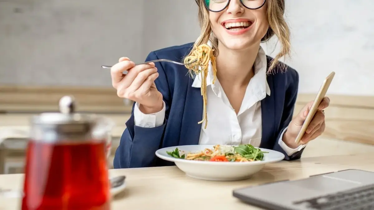 kobieta w okularach w marynarce je przy biurku obiad