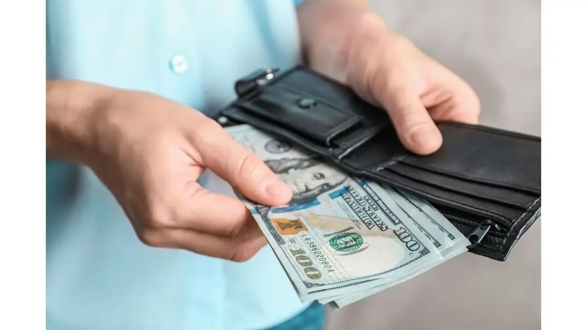 Dłonie trzymające portfel i pieniądze.