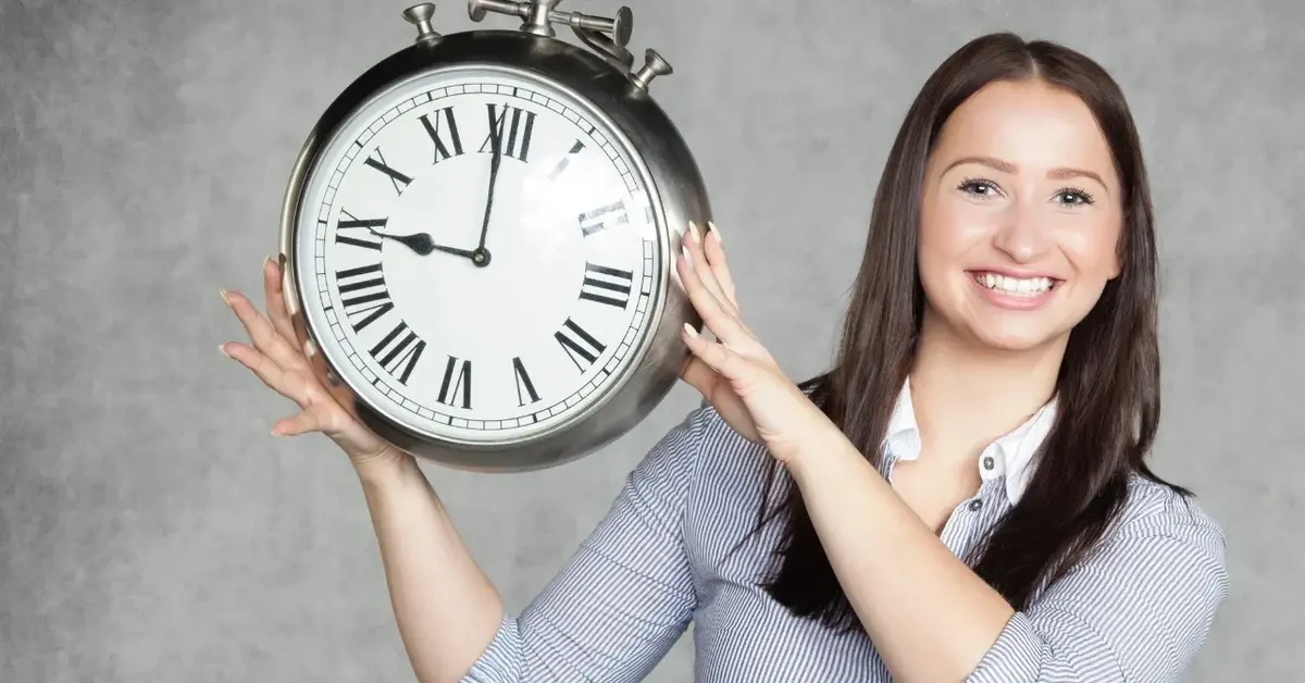 Kobiet trzymająca w rękach bardzo duży srebrny zegar