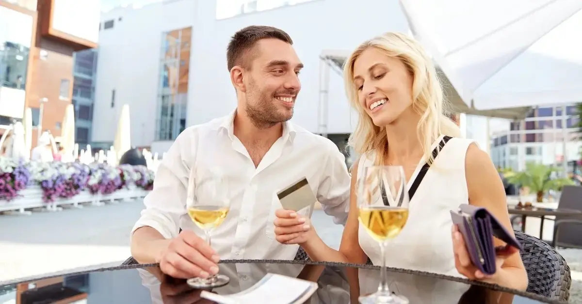 Kobieta i mężczyzna przy stoliku. Kobieta trzyma kartę kredytową w ręce 