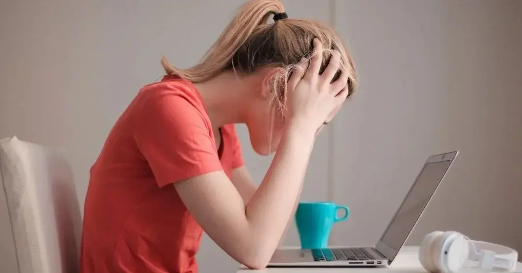 zestresowana kobieta w czerwonej koszulce przed komputerem 