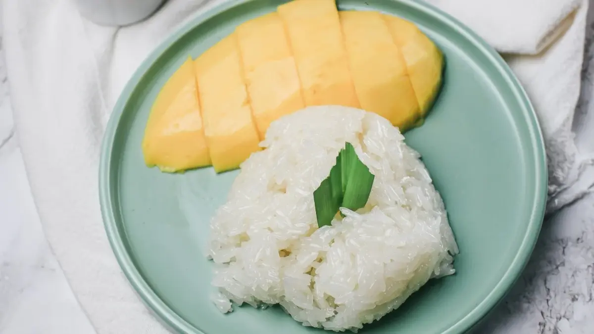ryż z mlekiem kokosowym na talerzu obok mango pokrojone