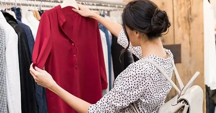 Kobieta przed wieszakiem szukająca ubrań do karmienia zgodnych z ciążowymi trendami w sklepie odzieżowym