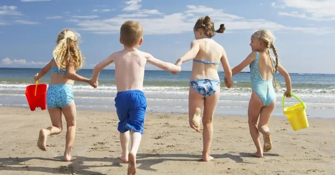 Dzieci są na wakacjach. Biegają po plaży.