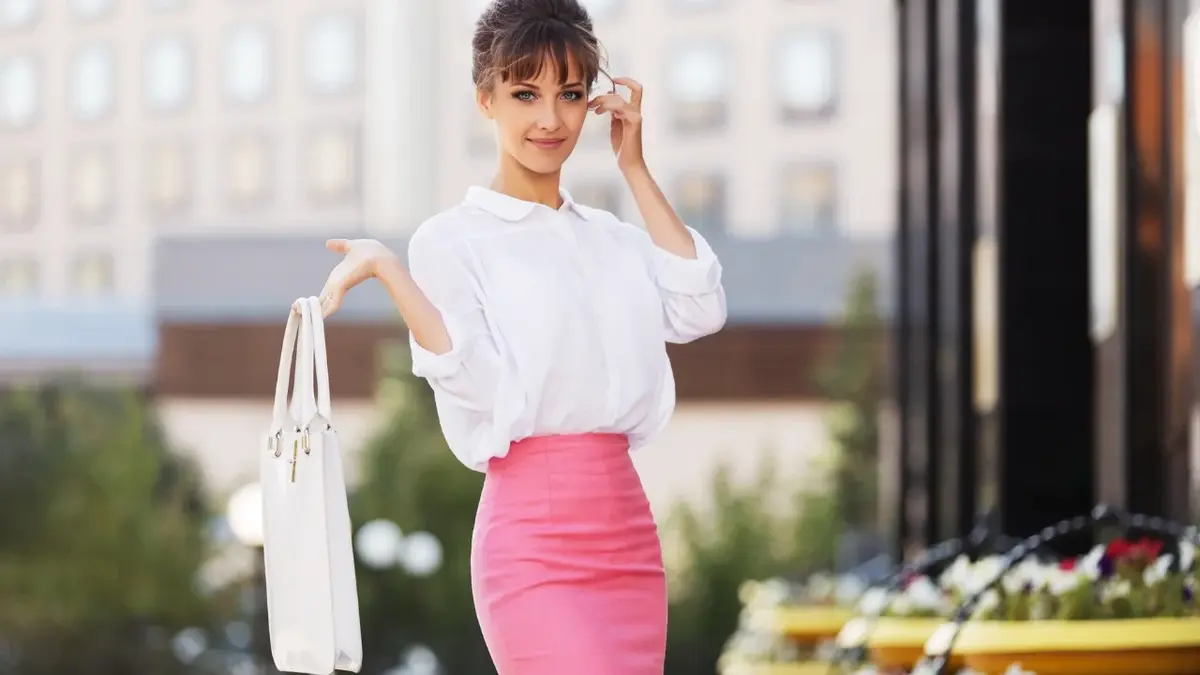 Kobieta w różowej ołówkowej spódnicy i białej bluzce