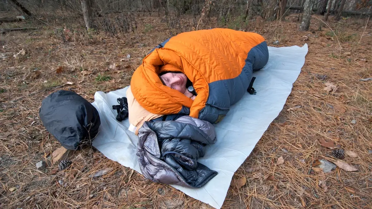 Mężczyzna w śpiworze na campingu 