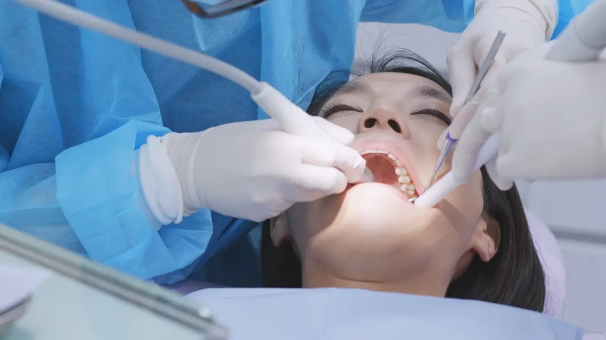 Kobieta na fotelu dentystycznym podczas zabiegu skalingu zębów