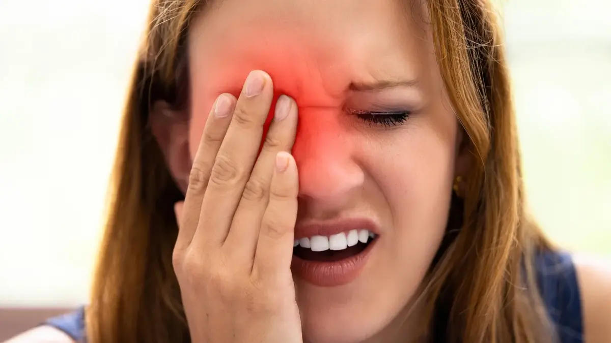 Kobieta trzymająca rękę na prawym oku, w tym miejscu nałożona czerwona grafika sugerująca ból