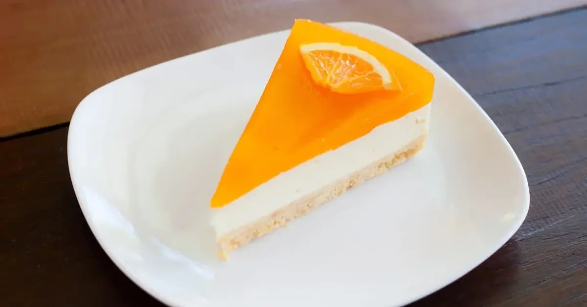 Porcja sernika pomarańczowego na białym talerzyku 