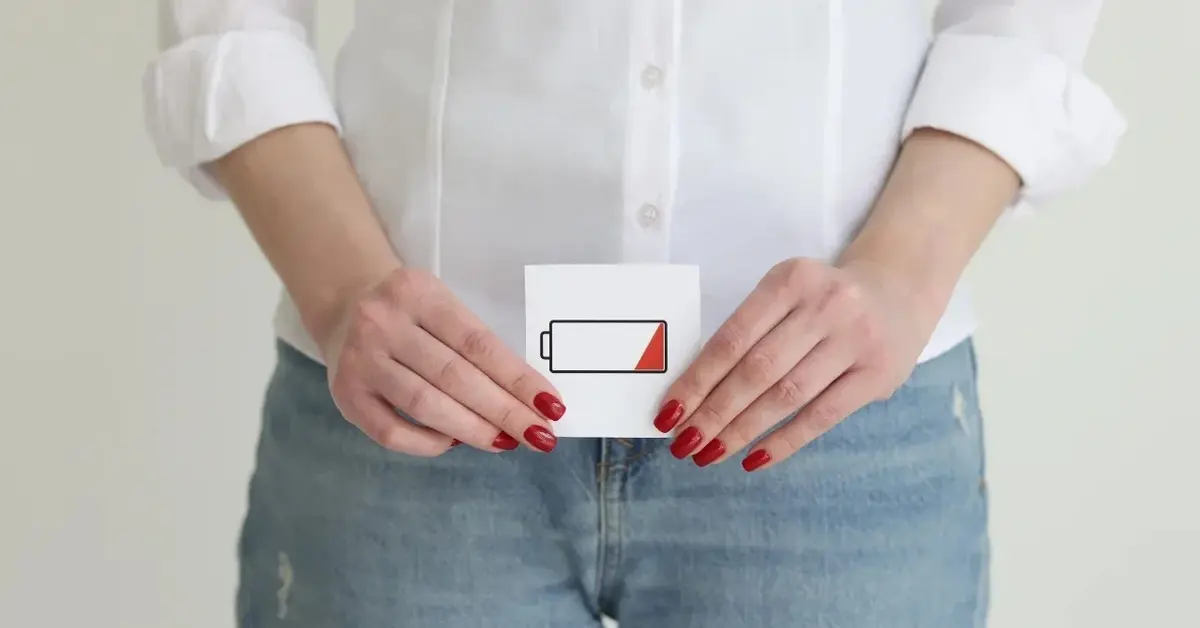 Kobieta trzymająca przed sobą karteczkę z symbolem wyczerpanej baterii