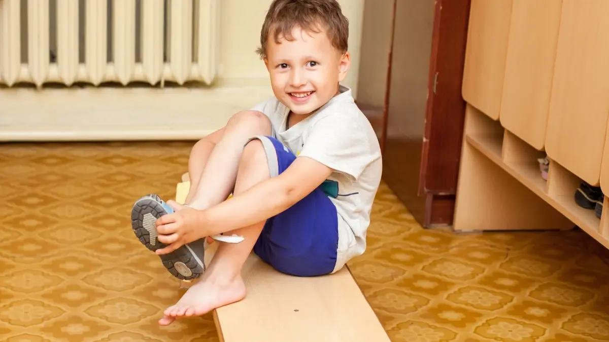 Chłopiec zakładający buty na ławeczce w szatni