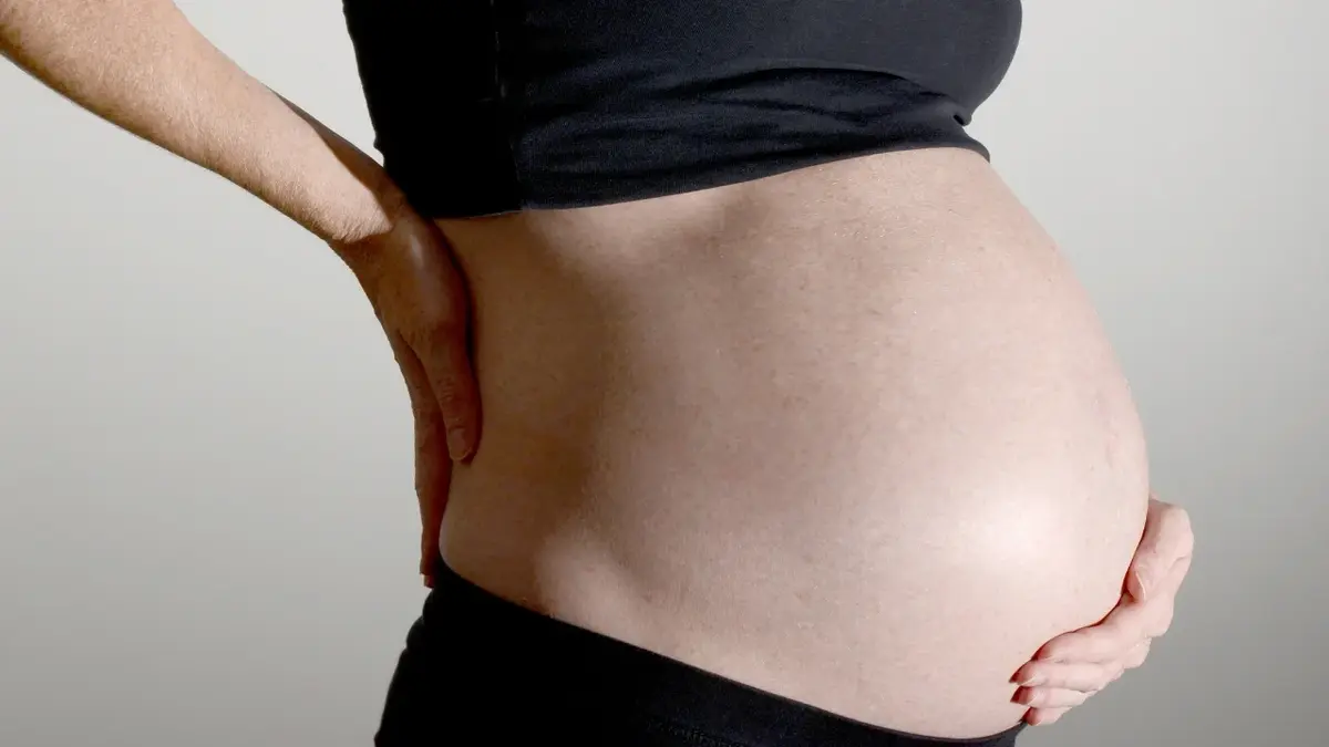 Kobieta w ciąży stojąca bokiem