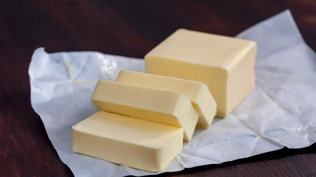 Masło pokrojone na kawałki na drewnianym blacie 
