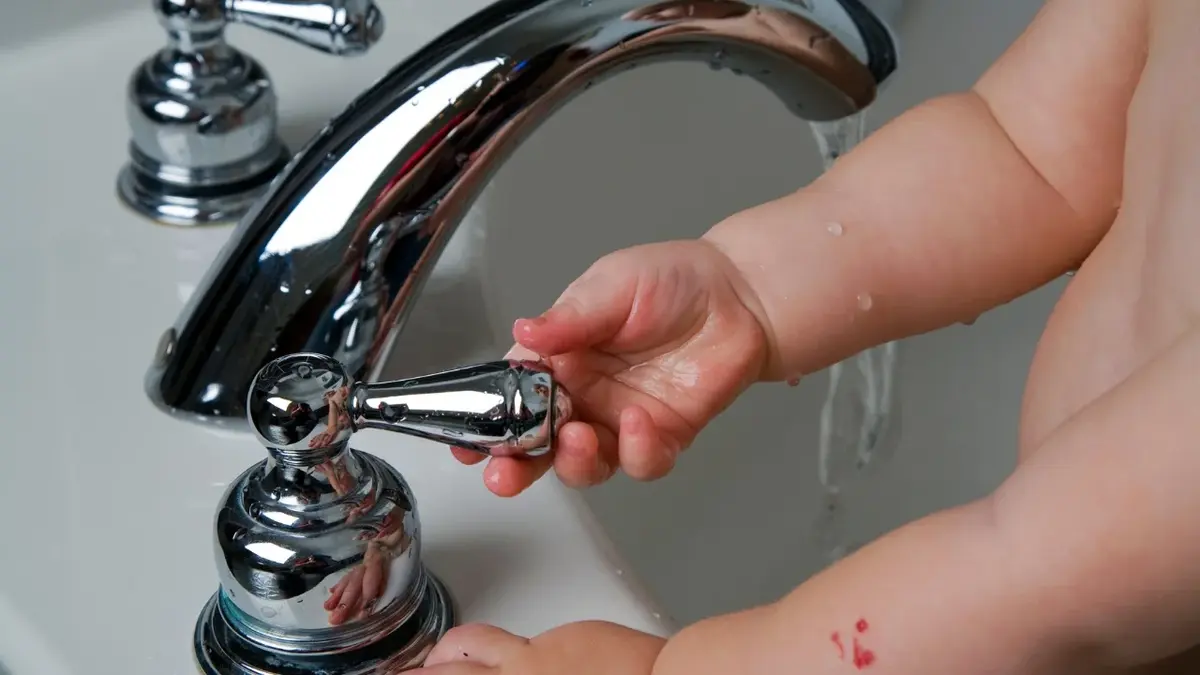 Naczyniaki na ręce małego dziecko odkręcającego wode w kranie