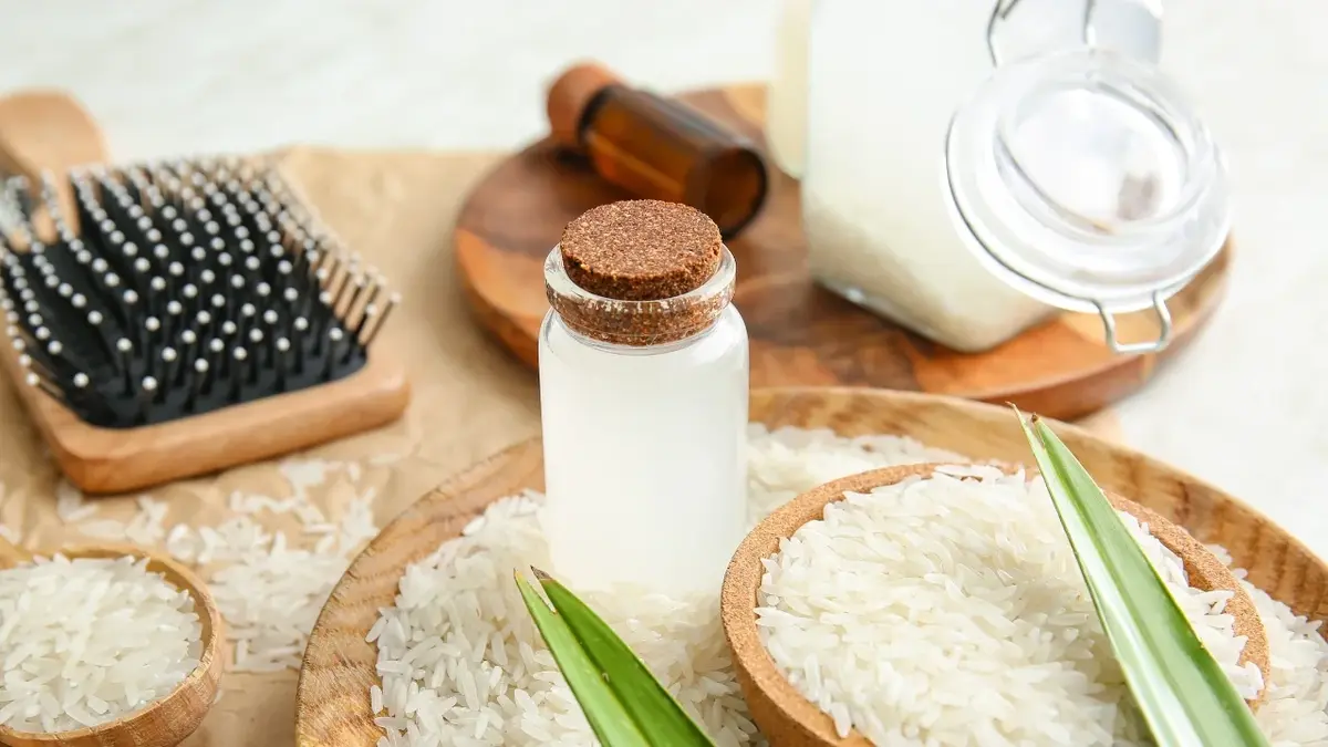 Woda ryżowa na włosy w buteleczce, obok miseczka z ryżem