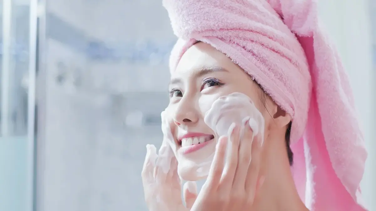 Dziewczyna z ręcznikiem na głowie myjąca twarz pianką