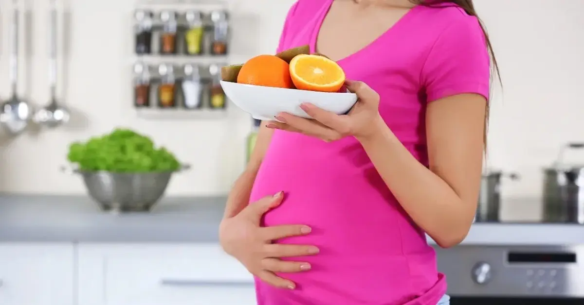 Kobieta w ciąży trzymająca w ręce talerzyk z 