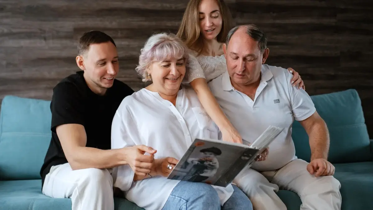Rodzina siedząca na kanapie oglądająca album ze zdjęciami 