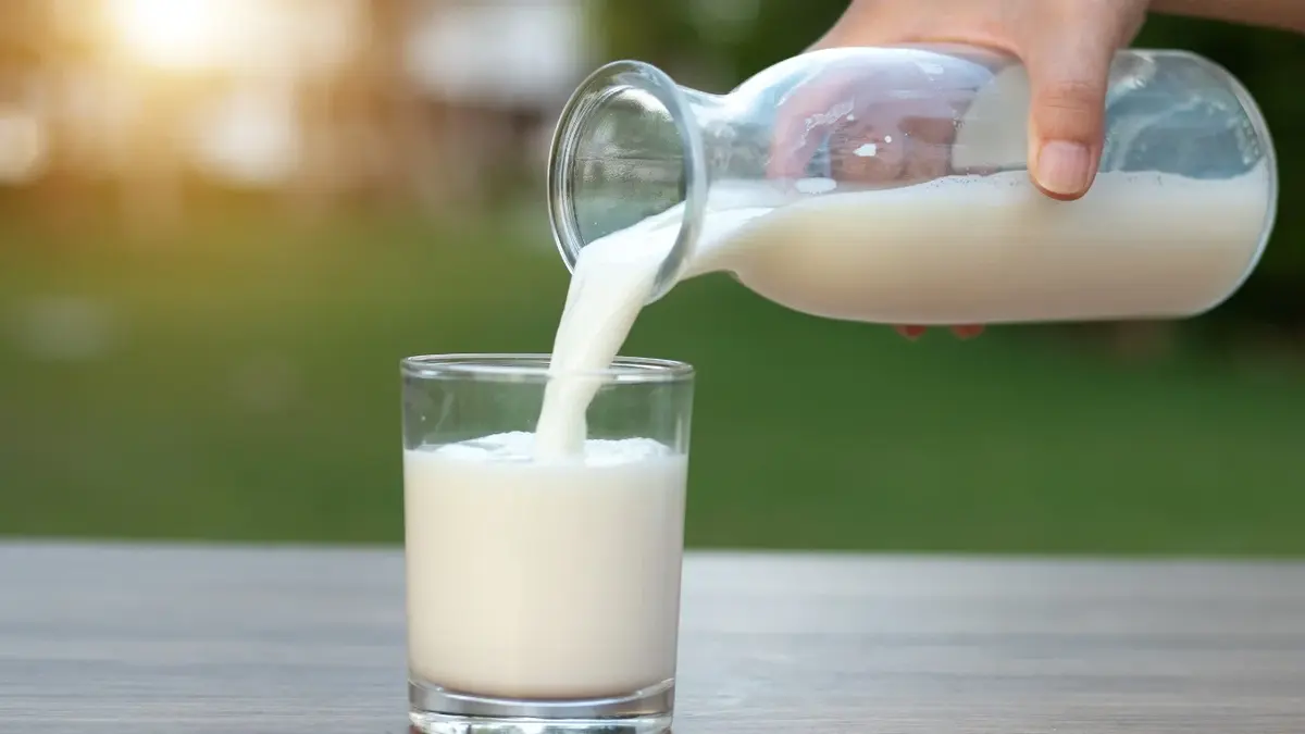 Mleko nalewane do szklanki ze szklanego dzbanka 