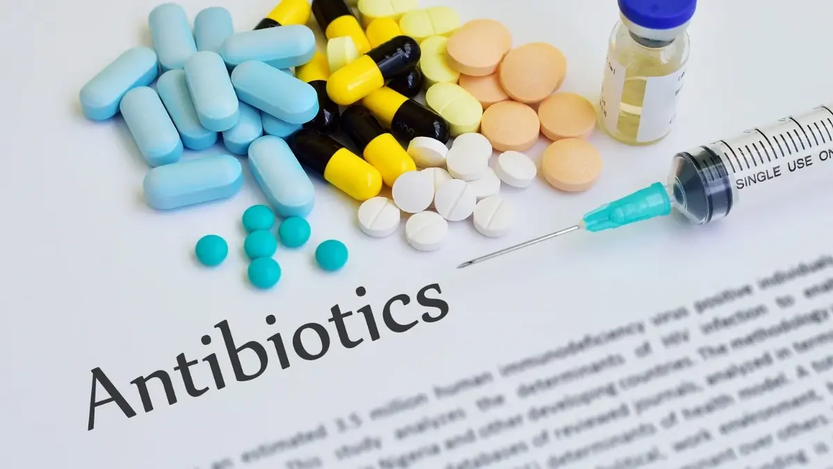 tekst z nagłówkiem antibiotics powyżej różne kolorowe tabletki i strzykawka z igłą