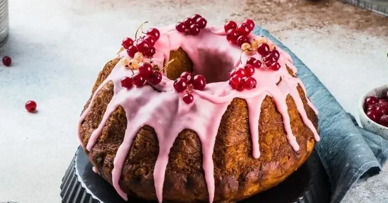 Świąteczna babka polana różowym lukrem i udekorowana porzeczkami