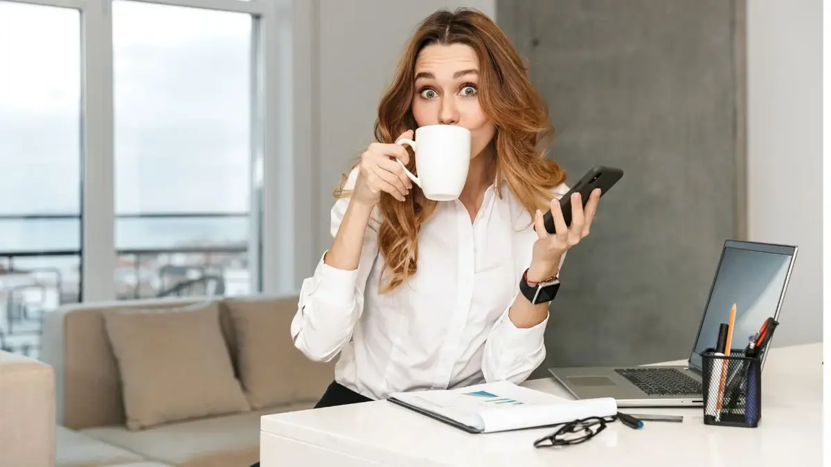 Kobieta pijąca kawę z filiżanki w domowym biurze