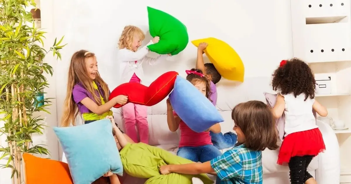 Dzieci bawią się kolorowymi poduszkami w domu.