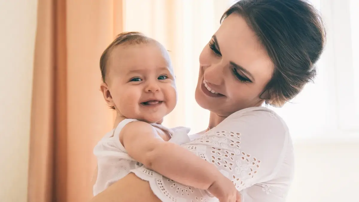 Kobieta trzymająca na rękach uśmiechnięte niemowlę 