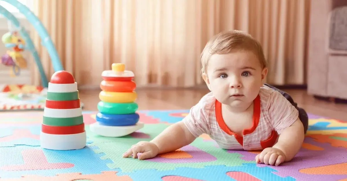 Niemowlę leżące na brzuszku na piankowej kolorowej macie 