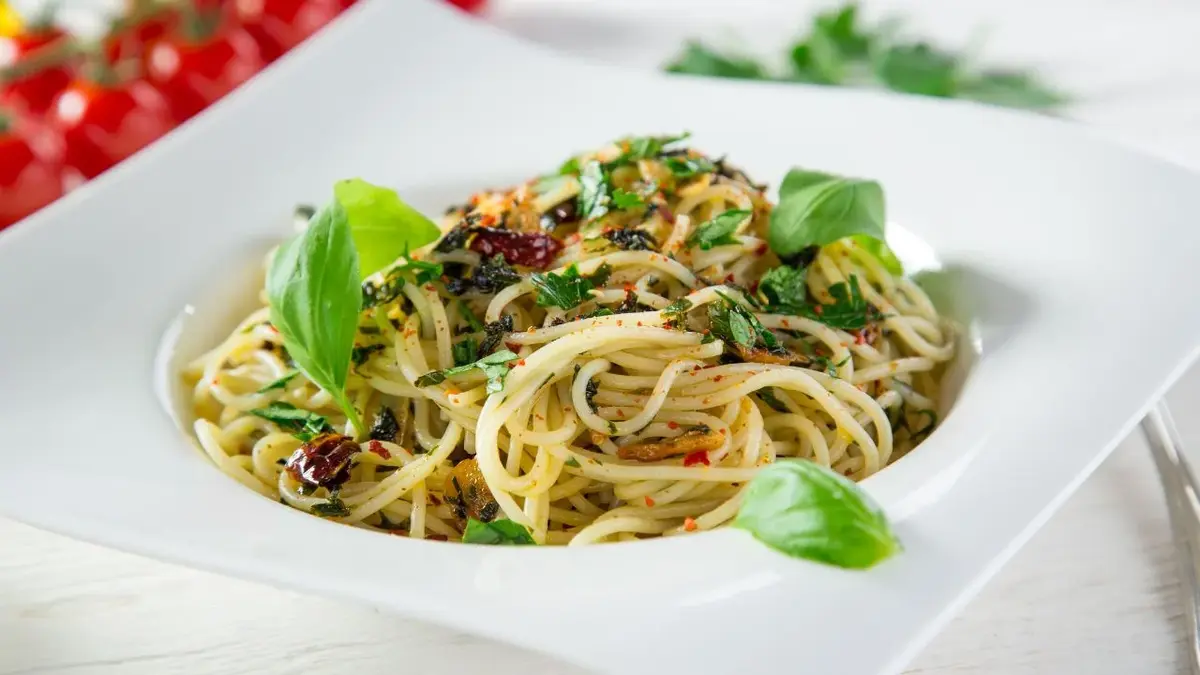 Porcja spaghetti aglio e olio podana w białym talerzu