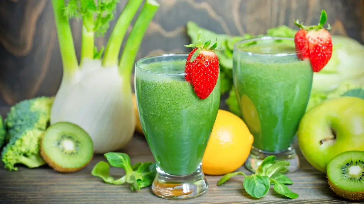 zielony sok z truskawkami na szklankach z tyłu różne zielone owoce i warzywa