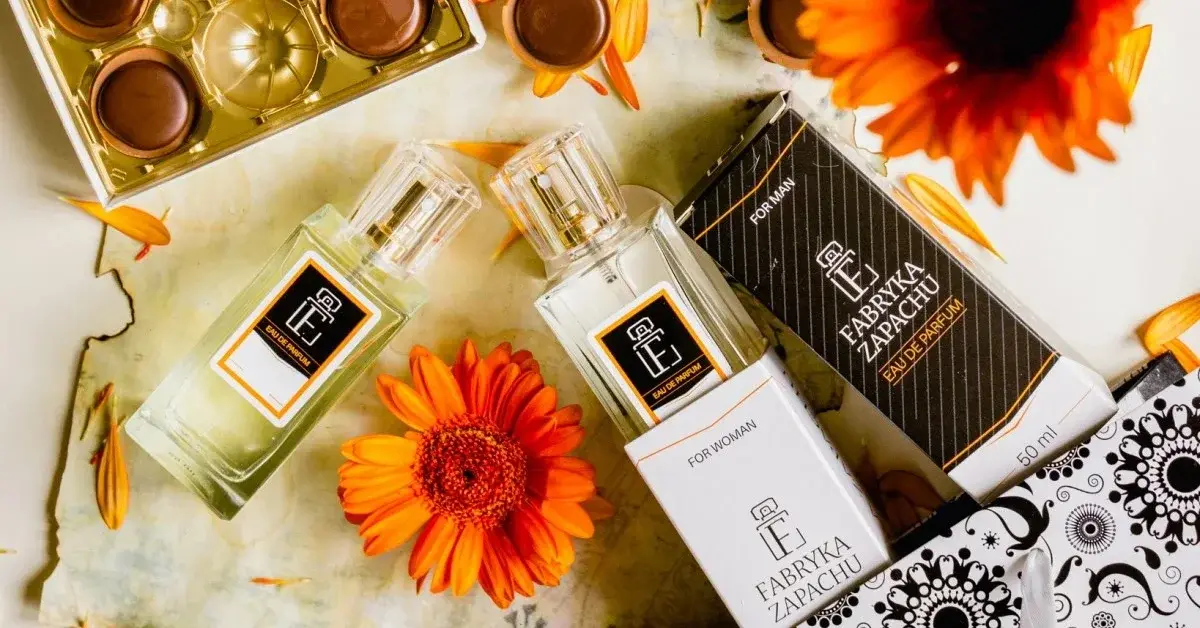 Na stole wśród czekoladek i pomarańczowych gerber rozłożone eleganckie odpowiedniki perfum w buteleczkach