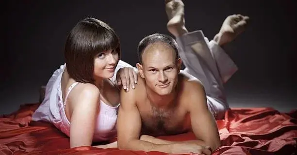 Kobieta i mężczyzna leżą na łóżku z czerwoną kapą