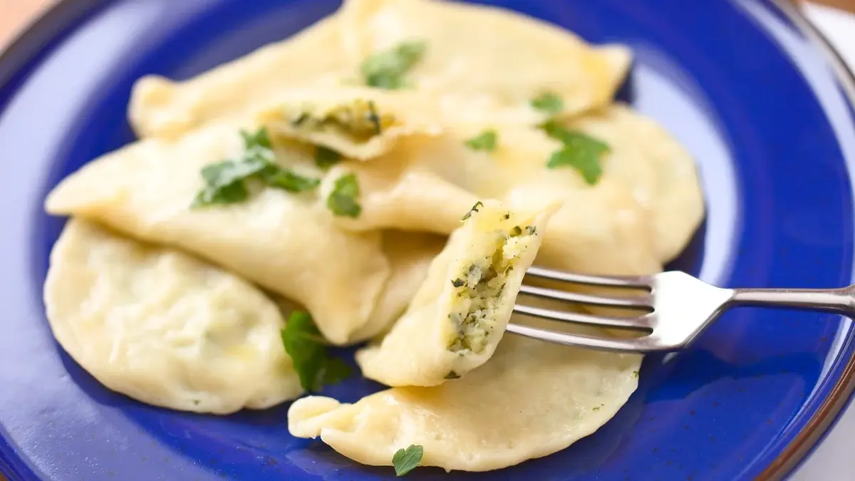 Pierogi ze szpinakiem i serem feta na niebieskim talerzu 